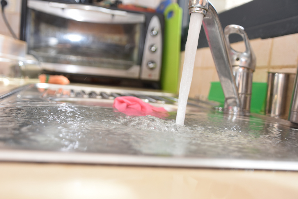 Overflowing kitchen sink in desperate need of drain cleaning service. 