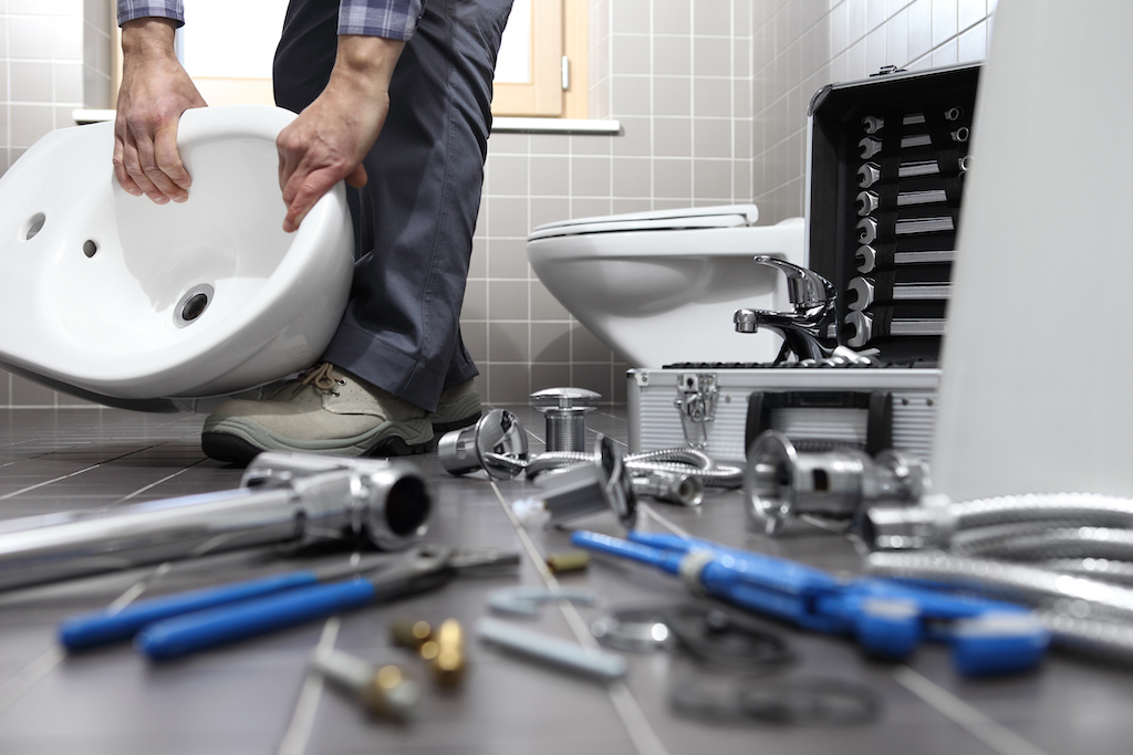 Residential plumbing repair, tools on ground. Plumber fixing toilet.