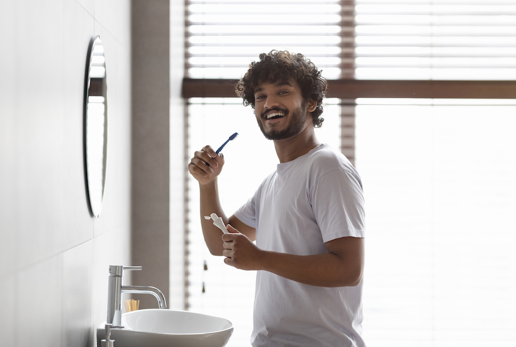 Happy man brushing his teeth in his newly renovated bathroom. | Bathroom Remodeling Services