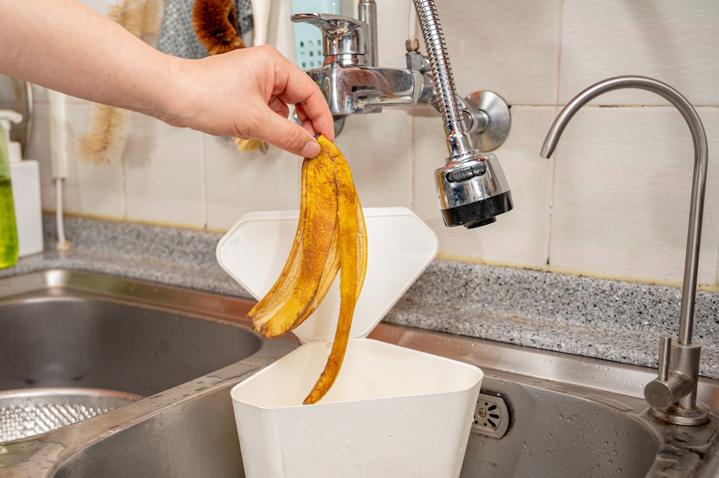 Person throwing banana peel in trash can instead of garbage disposal. | Garbage Disposal Repair And Installation