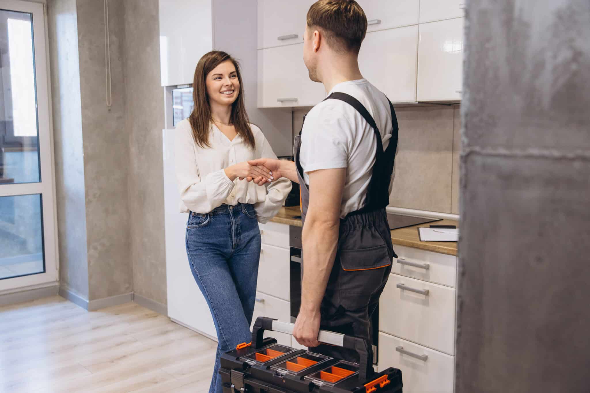 Plumbing Services, Plumber shaking hands with woman after finishing work in kitchen.