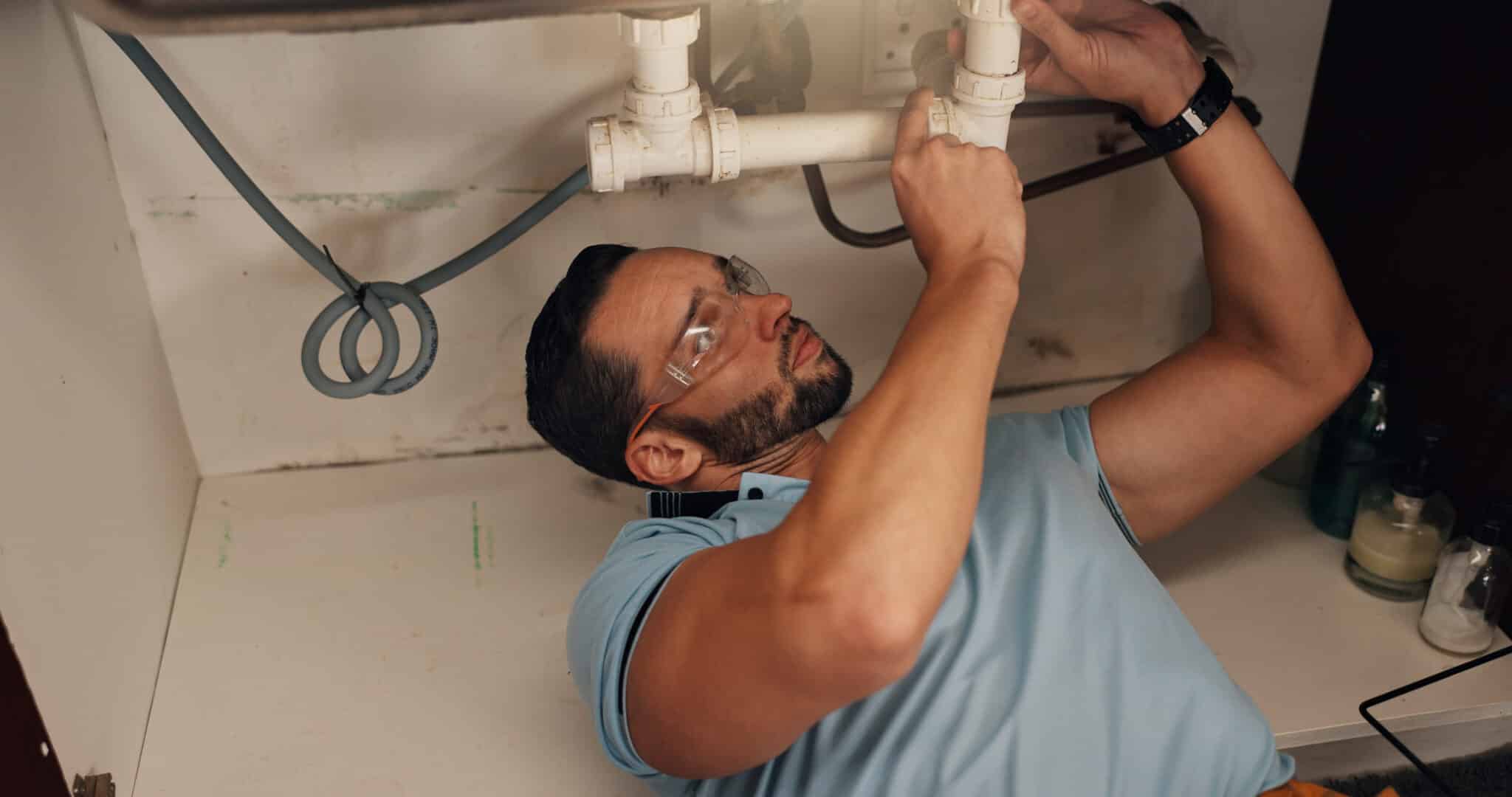 Man, plumber and assessment in kitchen, pipe and sink with search for leak, Plumbing Maintenance.